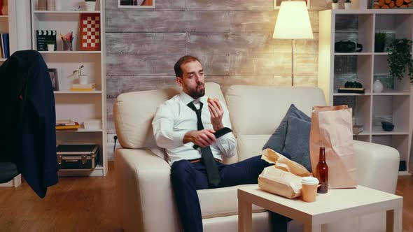Businessman in Suit Sitting on Couch Eating a Burger