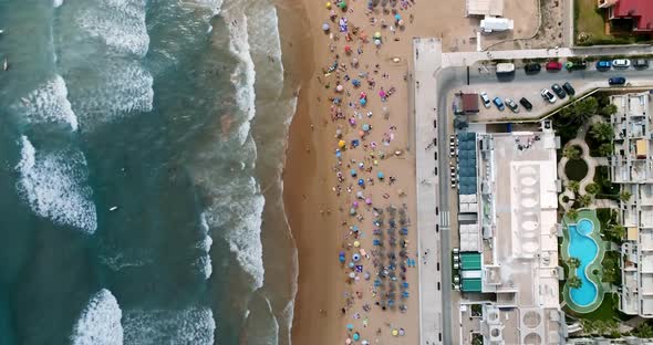 Drone Flying Over the Summer Beach Overlooking Tourists and Surfers Riding Waves