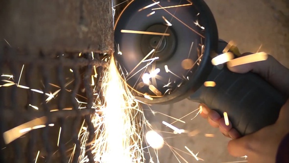 Closeup of worker using a grinder cuts metal in a workshop