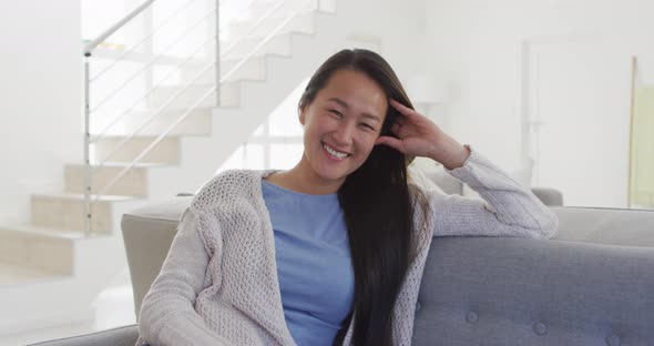 Happy asian woman sitting at sofa at home