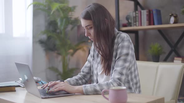 Young Brunette Caucasian Businesswoman Typing on Laptop Keyboard, Looking at Her Watch. Female