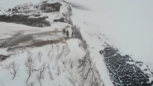 Aerial View of Winter Landscape, Snowy Peak of Mountain and Frozen River Down, Naked Trees