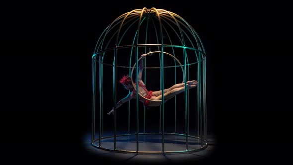 Girl Art Acrobatics on a Rotating Hoop in a Metal Cage, Black Background