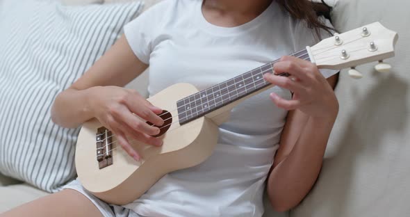 Woman practice ukulele at home