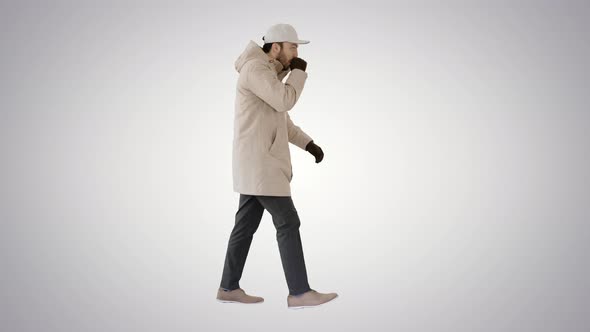 Caucasian Man in a Hat and Coat Coughing Walking on Gradient Background