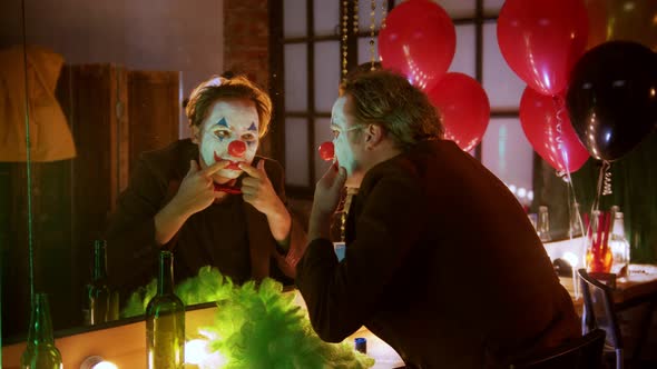 A Man Clown Stretches Out His Lips in a Smile and Laughing at Himself in the Mirror