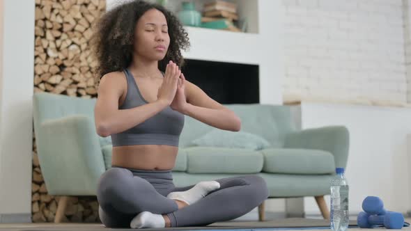 Peaceful Young African Woman Meditating on Yoga Mat at Home