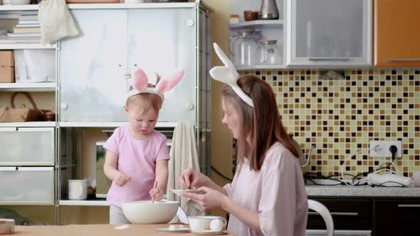 Happy Easter Joyful Family Mom and Daughter Wearing Bunny Ears Headbands Gathering at Table in