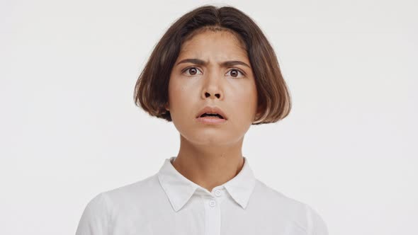 Young Beautiful East Asian Female in White Shirt Frighting and Sighing on White Background