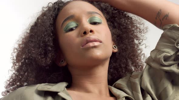 Young Mixed Race Model in Studio on White with Curly Hair, Bright Green Eye Makeup