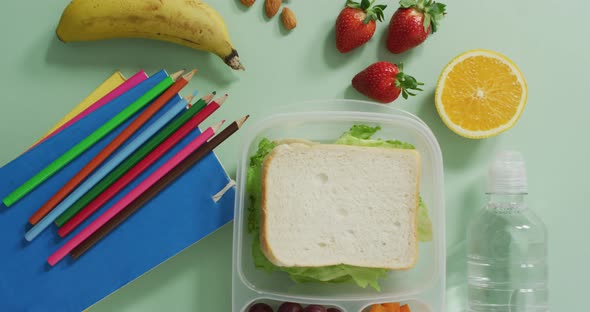 Video of healthy packed lunch of fruit and vegetables, with coloured pencils and notebooks