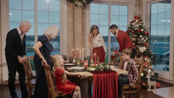 Grandparents with Their Children Sitting at the Table on Christmas Eve Laughing