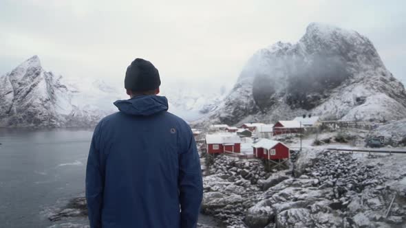 Man By Hamnoy Fishing Village With Olstinden Mountain