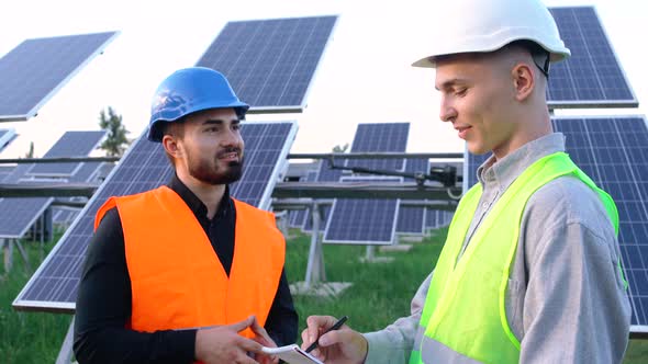 The Portrait of Two Engineers with the Project Plan at the Solar Farm.