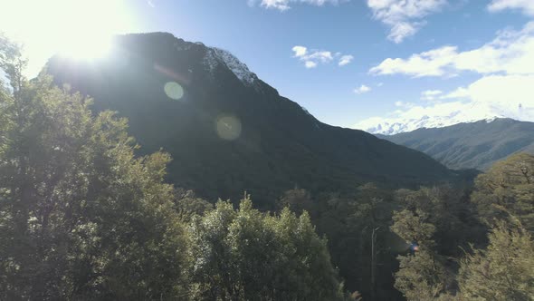 Panning shot of snow capped mountains and lush green forrest and valleys on a bright sunny day in Ne