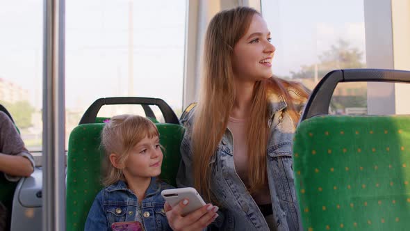 Mother with Daughter Traveling By Bus Going Home Playing on Smartphone Browsing Social Media