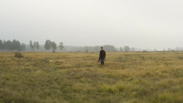 Male documentarist taking pictures in a foggy grassland,autumn,Czechia.