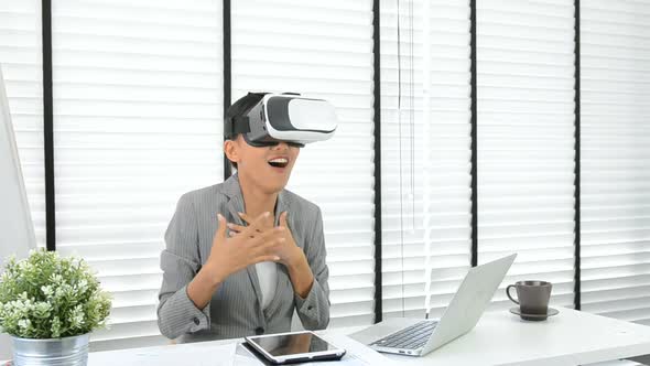 Asian woman use virtual reality glasses ( VR ) in her office