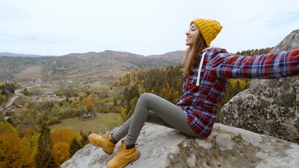 POV First Person View of Woman Hiker in Warm Casual Wear Sits on Edge of Cliff Against Background of