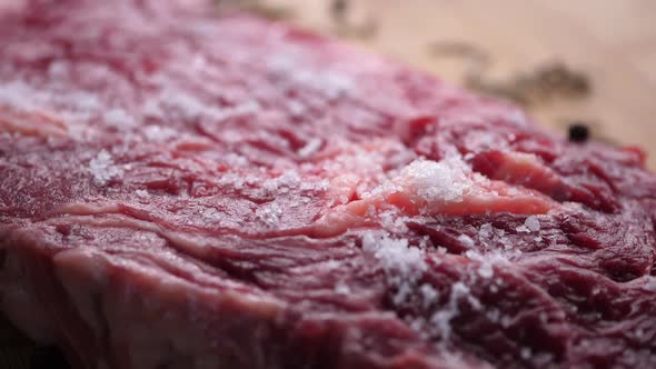 Salt Falling On Raw beef Steak On cutting Board
