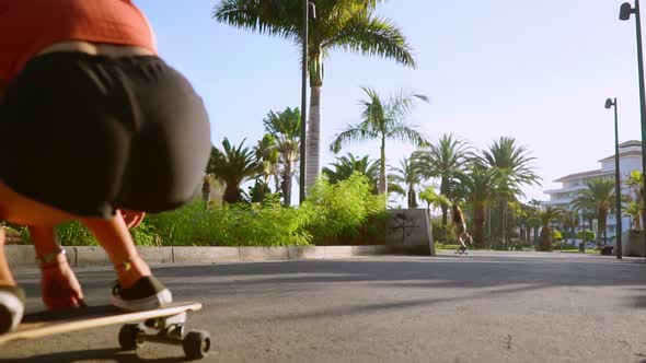 Two Female Friends on Skateboards Rides Downhill at the Resort Having Fun Moving and Smiling. Road