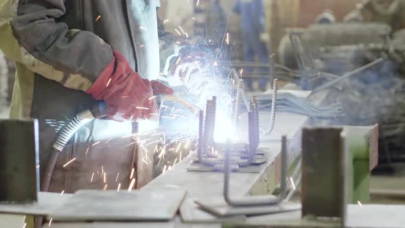 Factory worker welding steel rods