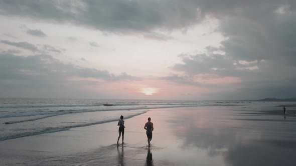 People Jogging on Oceanfront at Dusk