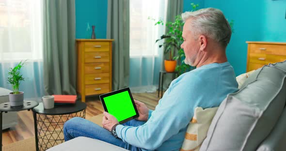 Adult Old Man at Home Uses Green Mockup Screen Tablet