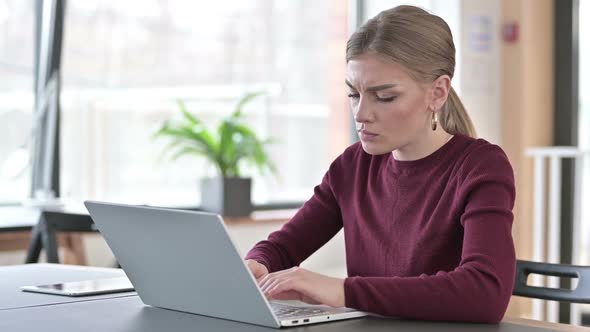 Pensive Young Woman Using Laptop in Office