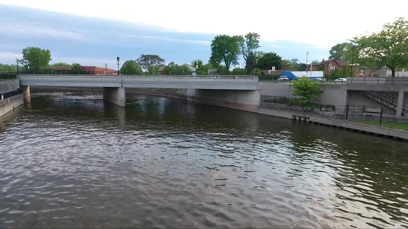 A drone flies low over the Flint River in downtown Flint, Michigan at dusk in summer.