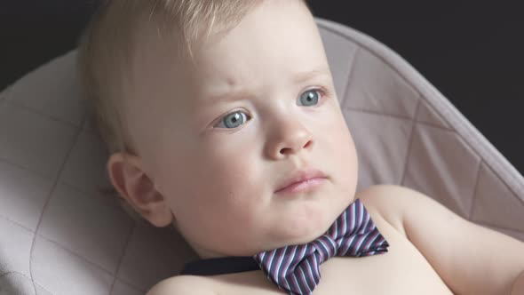 Cute Small Child Face Closeup One Year Old Baby Boy Wearing a Bow Tie Lying in Rocking Chair for