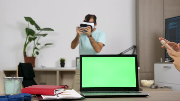 Laptop with Green Screen on the Table with a Beautiful Blonde Freelancer Woman Next To Ti