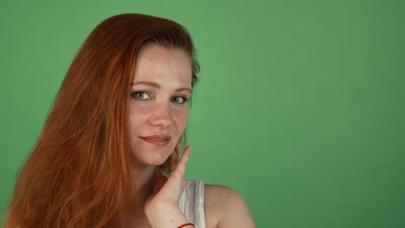 Gorgeous Woman with Long Ginger Hair Posing on Green Background