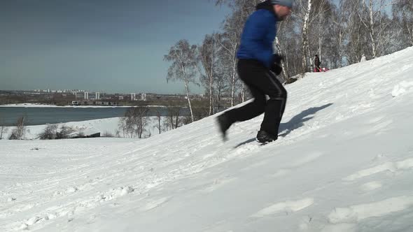 Side View Of Man Running Up The Hill In Winter