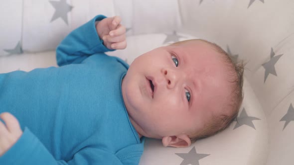 Worried Little Kid in Bodysuit Rests on Baby Cocoon in Room