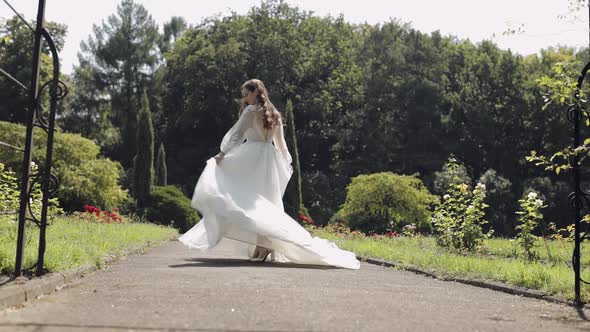 Beautiful and Lovely Bride in Wedding Dress and Veil in the Park Waiting for Groom