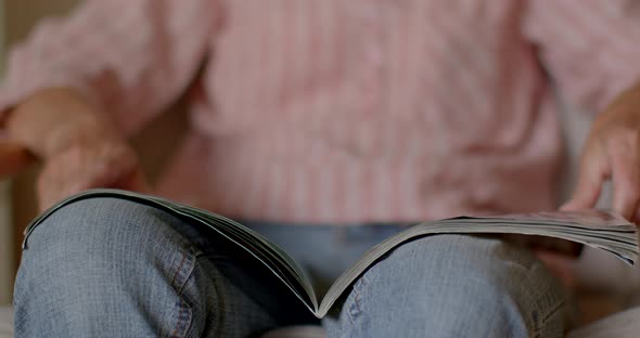 Closeup of Senior Woman of Retirement Age Reads Magazine While Sitting at Home