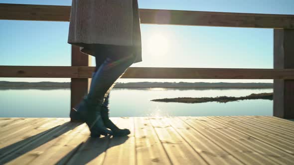 Side Closeup of Female Figure in Long Boots Walking on a Boardwalk