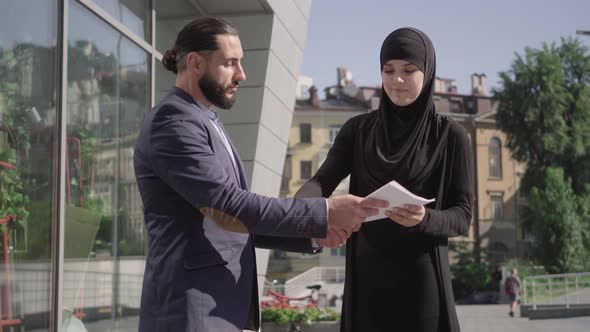 Positive Smiling Middle Eastern Man and Woman Shaking Hands Outdoors After Signing Business Deal