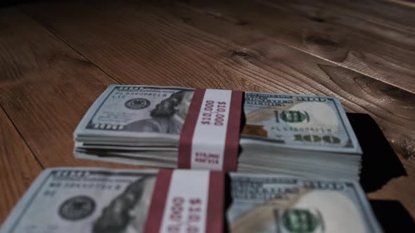 Three Stacks of 10000 American Dollars Banknotes in Bundles Lie on Wooden Table