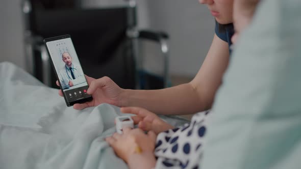 Mother Sitting Beside Sick Daughter During Online Videocall Meeting Teleconference