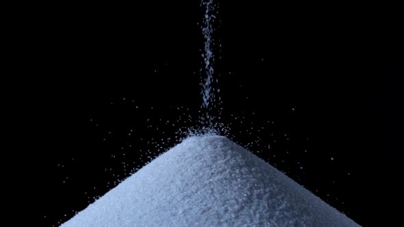 Particles of White Dry Sand are Pouring Down Forming a Hill on an Isolated Black Background with