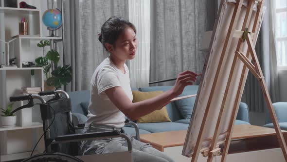 Asian Artist Girl In Wheelchair Holding Paintbrush Mixed Colour Thinking And Painting On The Canvas