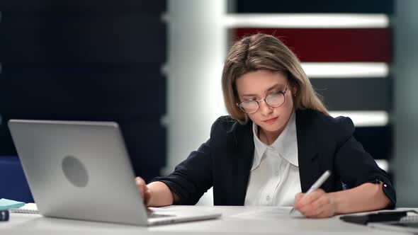 Confident Woman Writing Paper Document Use Laptop at Modern Workplace