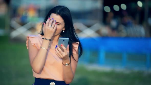 Young Women in a Park is Holding a Smartphone and Typing