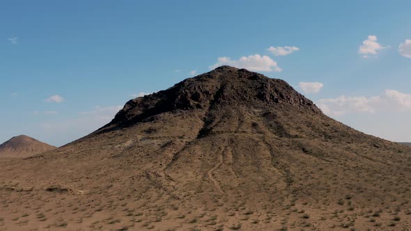 Fly over of rugged mountaintop revealing vast Mojave Desert, Aerial Dolly Zoom