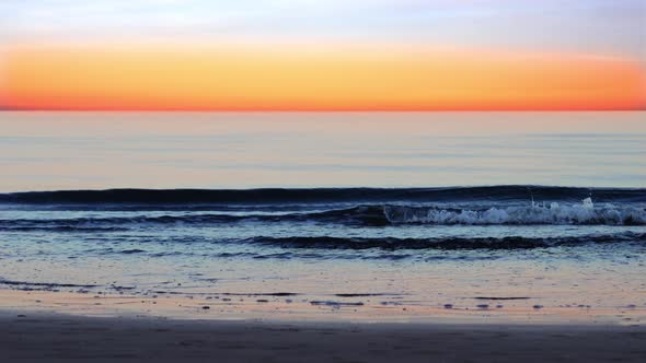 Sea Waves Roll on Beach Against Picturesque Sunset Sky