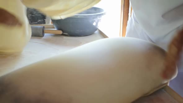 Closeup Slow Motion Oriental Women Simultaneously Twist and Rotate Thin Rolled Dough on Their Hands