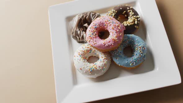 Video of donuts with icing on white plate over pink background