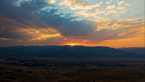 Aerial drone timelapse, majestic sun setting behind hills with dramatic clouds